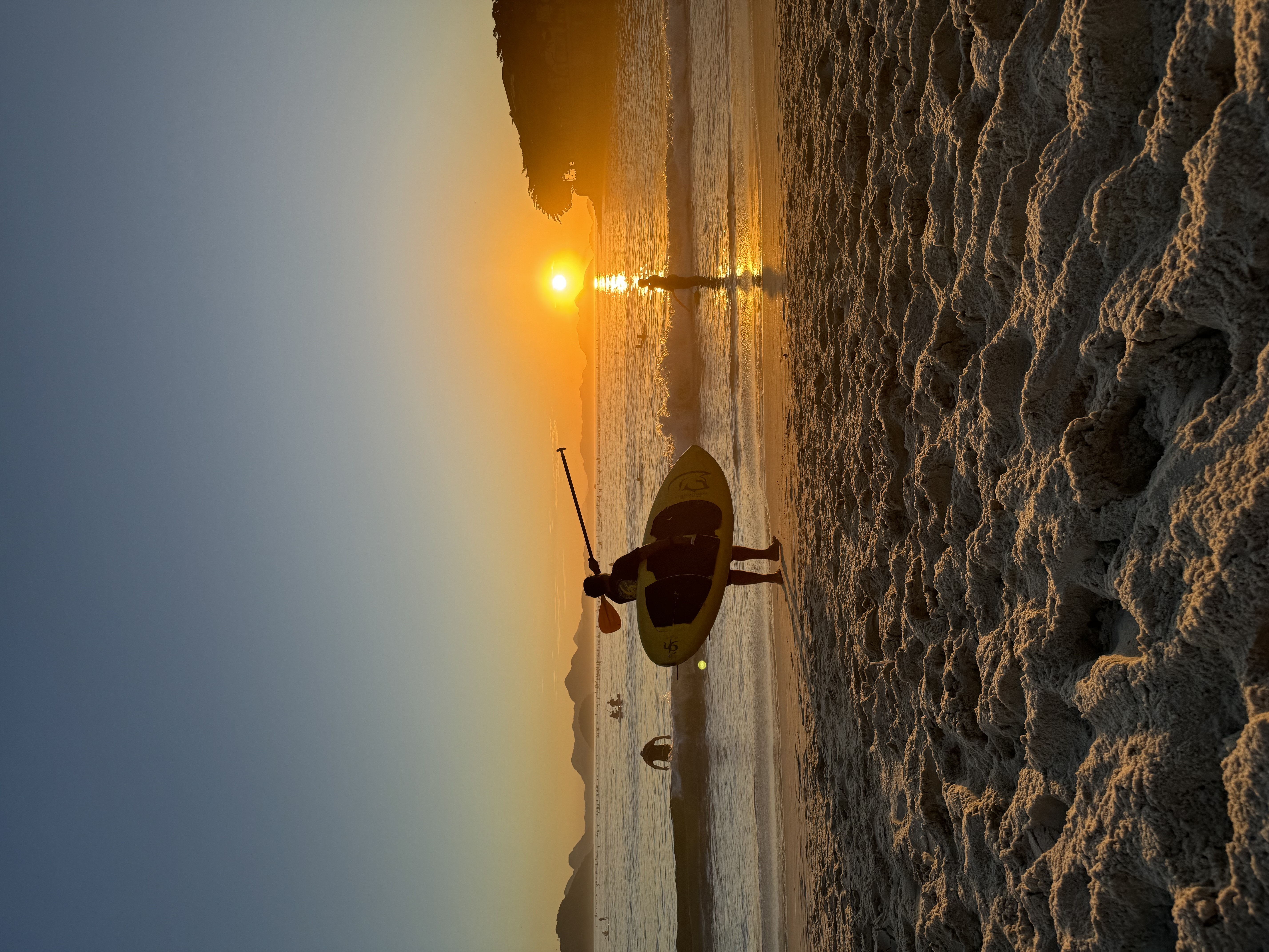 A person holding a surfboard as they look out to the sunrise
