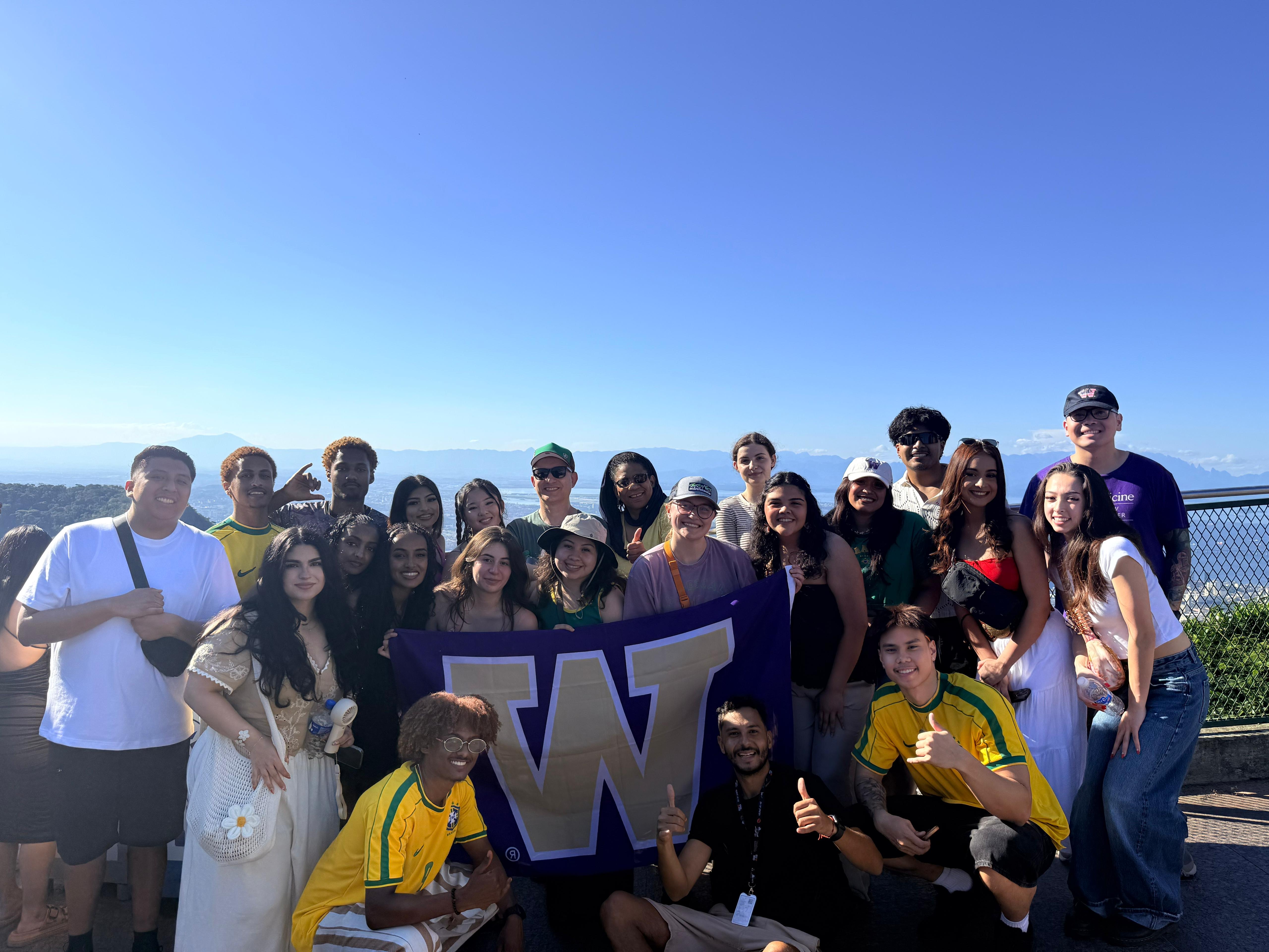 Laysha with a group of UW students holding a UW flag
