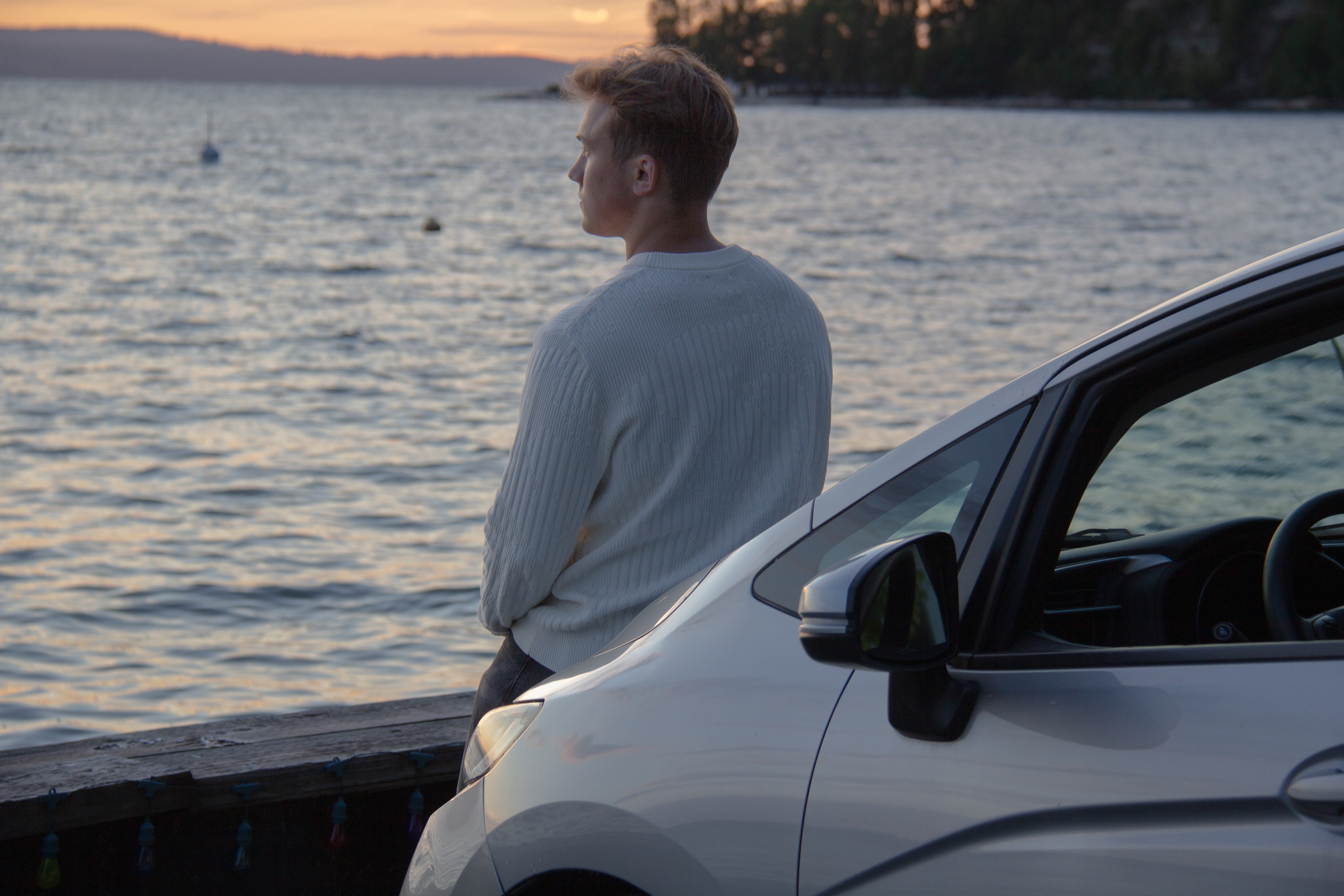 looking out over water and leaning on car